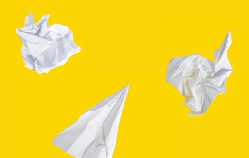 Iterations of crumpled paper planes on a yellow background