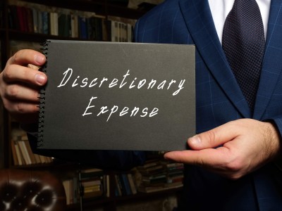 Man holding a notebook that says discretionary expense. 