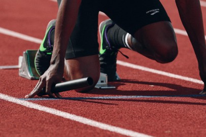 Runner gets ready to start his race on a red track. A metaphor for monitoring project portfolio performance. 